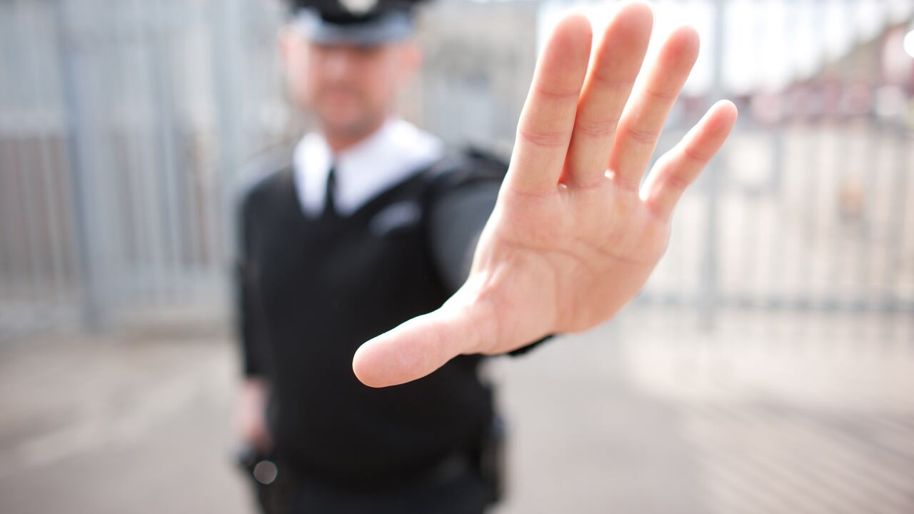 Guardia de seguridad en gesto de rechazo al paso de otra persona.