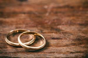 Un par de anillos de bodas de oro sobre fondo de madera, espacio de copia