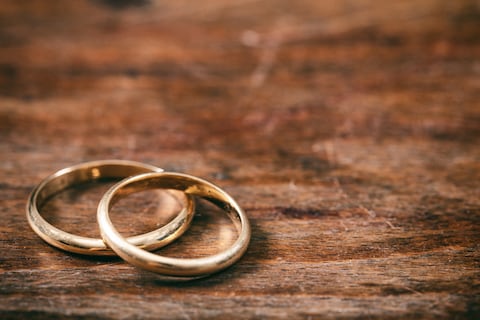 Un par de anillos de bodas de oro sobre fondo de madera, espacio de copia