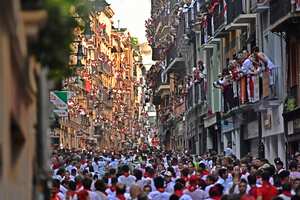 Gente corriendo por la calle por delante de los toros bravos en el primer día de encierros en las fiestas de San Fermín, Pamplona, en el norte de España, el jueves 7 de julio de 2022. Foto AP/Álvaro Barrientos