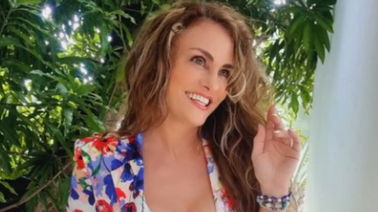 La actriz y ahora modelo de Only Fans, Aura Cristina Geithner posa junto a los árboles con una chaqueta de flores.