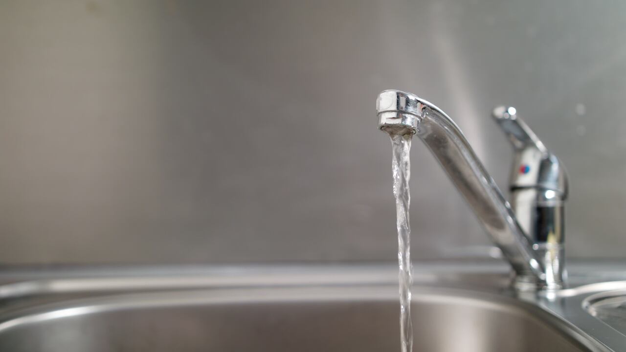 Agua que corre de un grifo a un fregadero. Fotografía de cerca