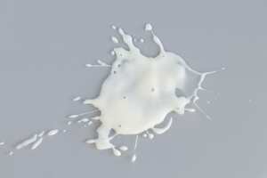 Splash of spilled white liquid on gray background top view