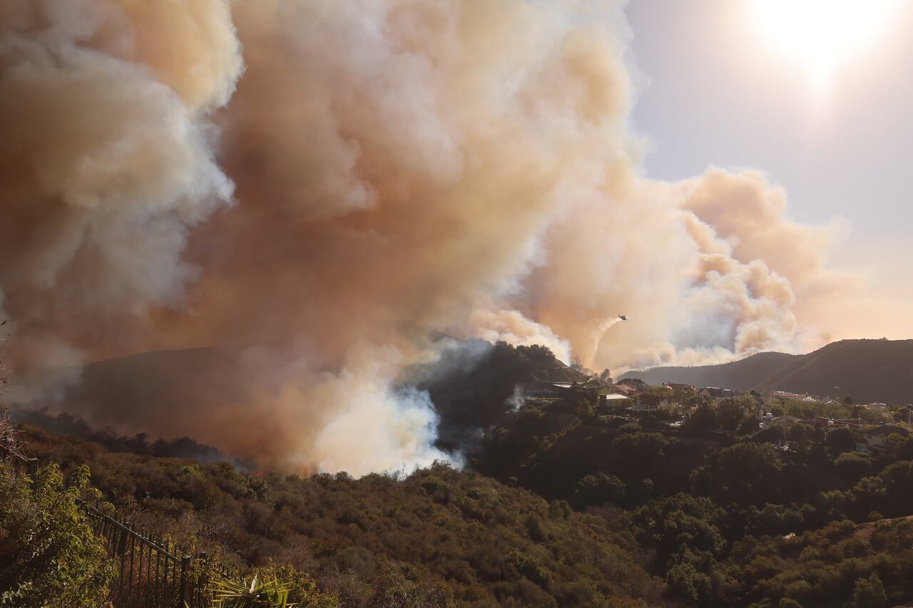 Un helicóptero arroja agua sobre las casas amenazadas por el incendio Palisades.
