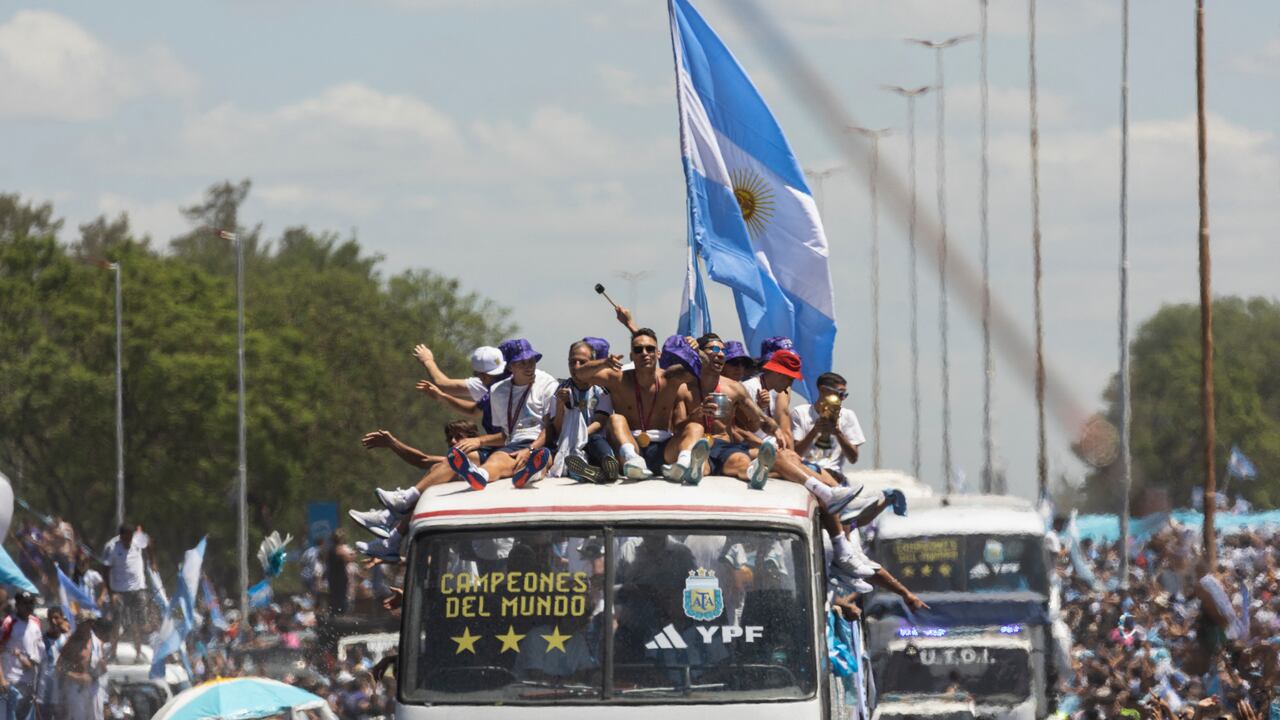 Argentina's players celebrate on board a bus with a sign reading "World Champions" with supporters after winning the Qatar 2022 World Cup tournament as they tour through Buenos Aires' downtown on December 20, 2022. - Millions of ecstatic fans are expected to cheer on their heroes as Argentina's World Cup winners led by captain Lionel Messi began their open-top bus parade of the capital Buenos Aires on Tuesday following their sensational victory over France. (Photo by TOMAS CUESTA / AFP)