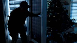 Esta foto ilustra un robo o un ladrón que irrumpe en una casa por la noche a través de una puerta trasera durante la temporada navideña. Vista desde el interior de la residencia.