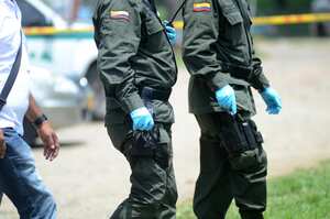 Dos policías recogen evidencias tras la explosión de un artefacto en el CAI del barrio Mojica, oriente de Cali.